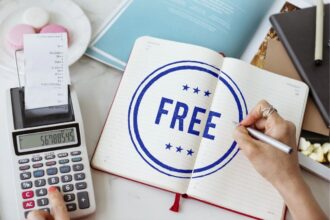 A woman doing financial calculations, while writing the words "free" in a notebook on her desk.