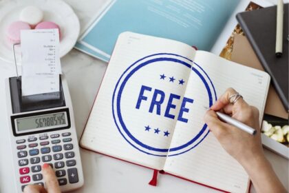 A woman doing financial calculations, while writing the words "free" in a notebook on her desk.